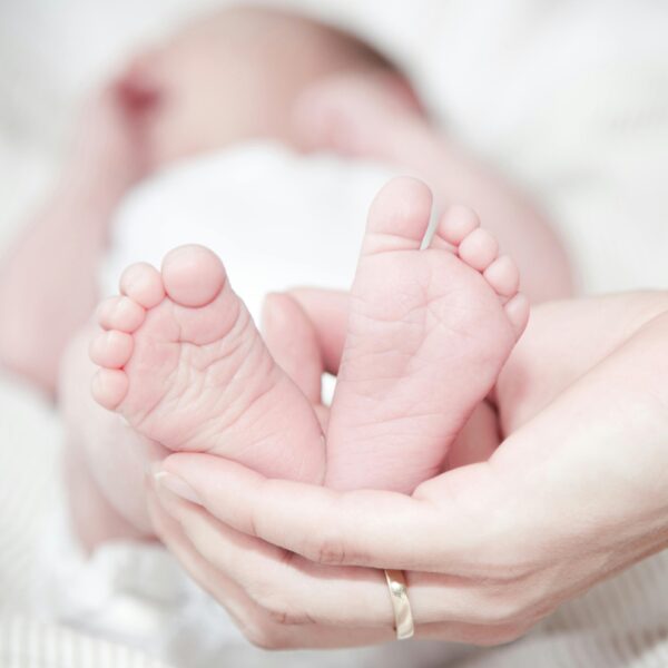 Tender photo of a mother's hands holding her newborn's feet, symbolizing love and care.